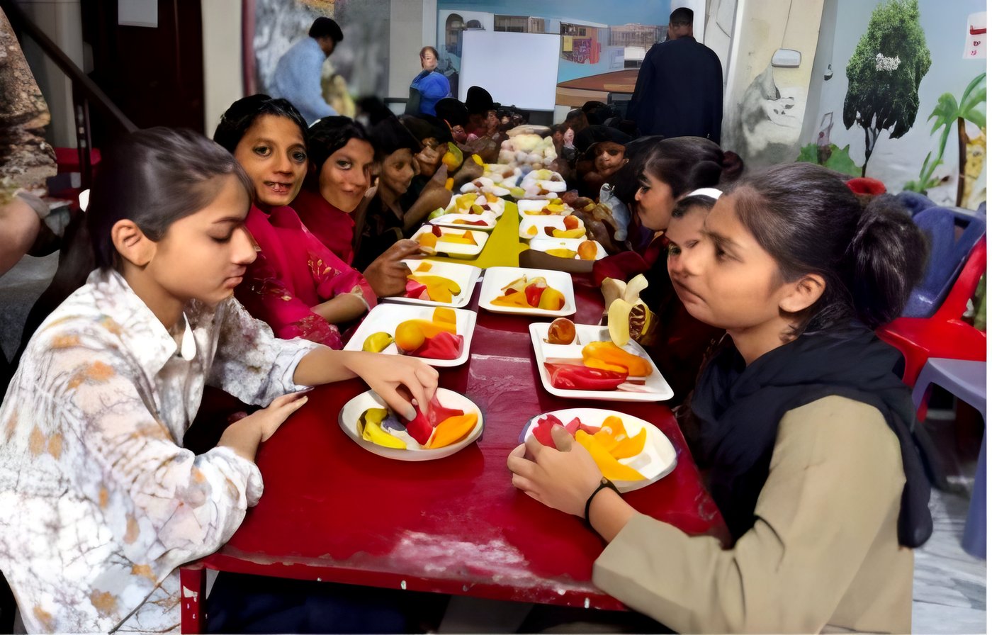 Children sharing plates of fruit at a long table